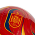 Close-up of a glossy red soccer ball featuring the Royal Spanish Football Federation crest in yellow and red, with a single gold star above it.