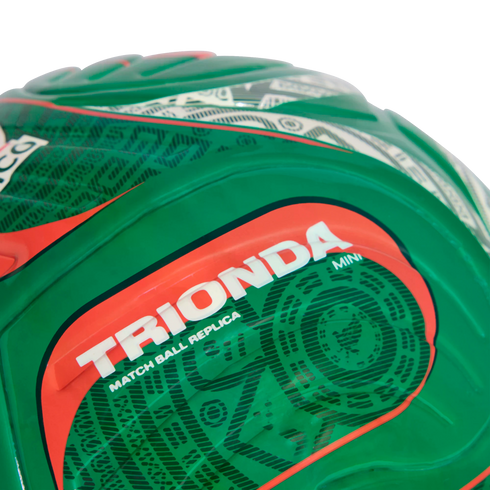 Close-up of a green soccer ball featuring the text "TRIONDA" in bold white letters on a red background, with "MATCH BALL REPLICA" and "MINI" printed below.