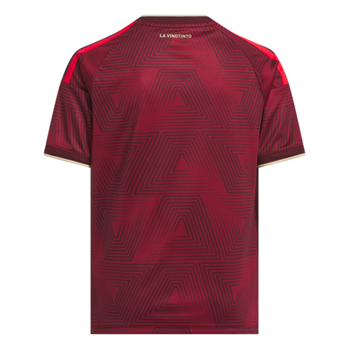 The back of a maroon soccer jersey with a geometric line pattern. It features "LA VINOTINTO" in gold text, red shoulder stripes, and cream trim on the collar and cuffs.