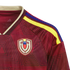 Close-up of a maroon Adidas Venezuela national soccer jersey with a geometric pattern, the team crest, and yellow and blue shoulder stripes.