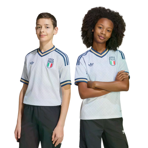 A boy and a girl posing in light blue Adidas Italy national team soccer jerseys and dark bottoms against a black background.