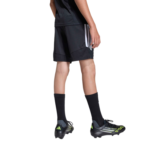 Rear view of a person wearing black Adidas athletic shorts and t-shirt, tall black socks, and black and neon yellow soccer cleats against a plain gray background.