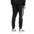 Back view of a person wearing black Adidas track pants with white side stripes and white sneakers.