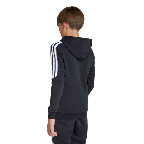 Rear view of a boy in a black Adidas hoodie with white stripes on the sleeves and matching sweatpants, standing against a plain light gray background.