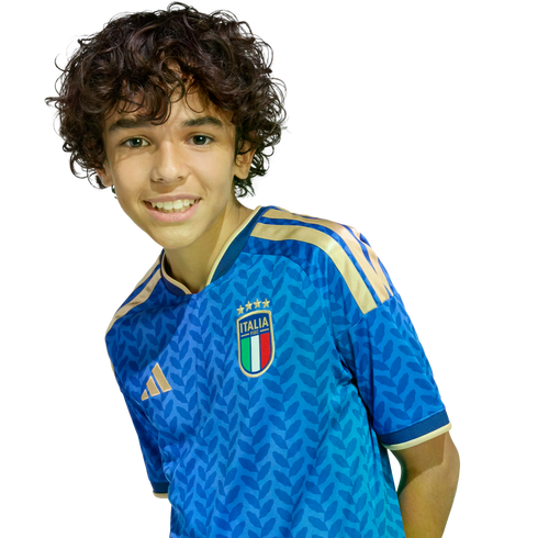 Smiling boy with curly brown hair wearing a blue Italy soccer jersey against a black background.