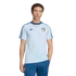 A young man with curly brown hair wearing a light blue Adidas Italy national team t-shirt and dark blue track pants, posed against a solid black background.