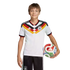 A smiling boy in a German national soccer uniform holds a colorful soccer ball against a black background.