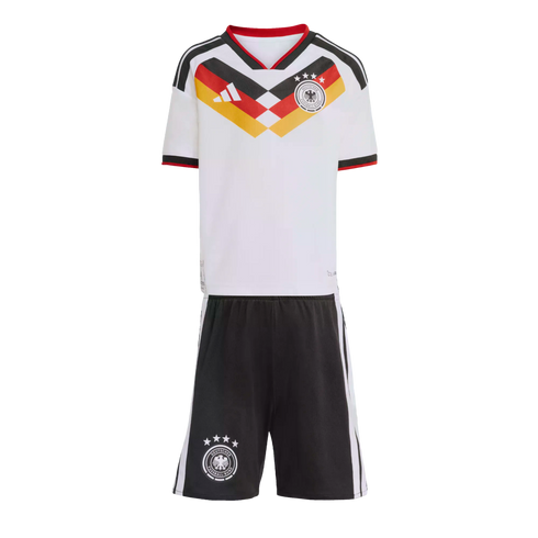 A kids' Germany home football kit with a white jersey featuring a black, red, and yellow chevron pattern and team crest, and black shorts with white side stripes.