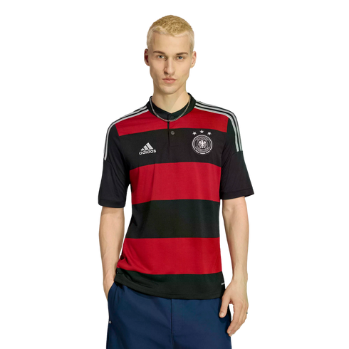 A young blonde man wears a red and black striped Adidas Germany jersey and dark blue shorts, posing against a white background.