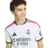 Smiling young man with curly hair wearing a white Real Madrid soccer jersey with green and pink accents.
