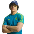 A man in a blue Adidas cap and teal soccer t-shirt with yellow stripes, posing with his arms crossed against a black background.