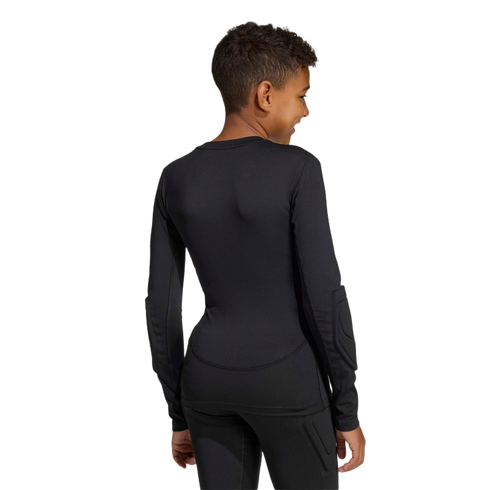 Back view of a youth in a black long-sleeved padded athletic shirt and matching pants, smiling over their shoulder against a plain background.