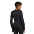 Back view of a youth in a black long-sleeved padded athletic shirt and matching pants, smiling over their shoulder against a plain background.
