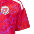 Close-up of a red sports jersey with a purple abstract pattern, white shoulder stripes, and a shield-shaped crest featuring the letters "CR".