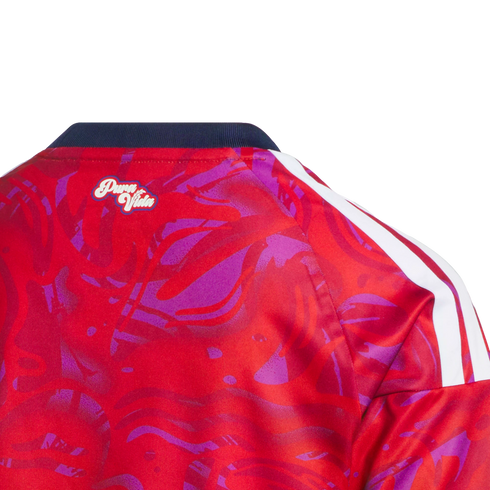 Close-up back neck view of a red and purple patterned jersey with a navy collar, "Pura Vida" script logo, and white shoulder stripes.