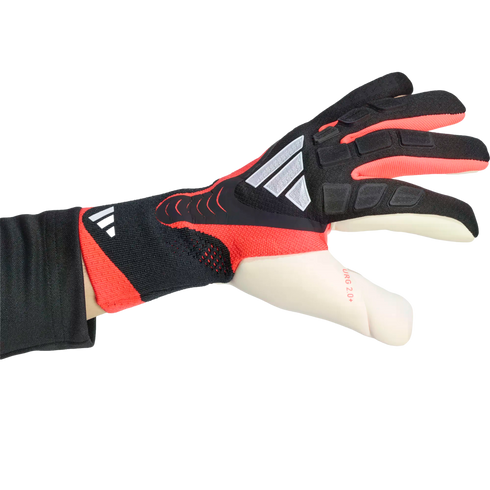 Side view of a black, red, and white Adidas goalkeeper glove on a hand. Features textured grip zones and "URG 2.0+" branding on the thumb.