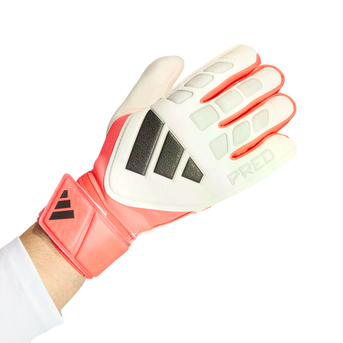 White and coral Adidas Predator goalkeeper glove on a hand, featuring dark grey stripes and a textured backhand, set against a solid black background.