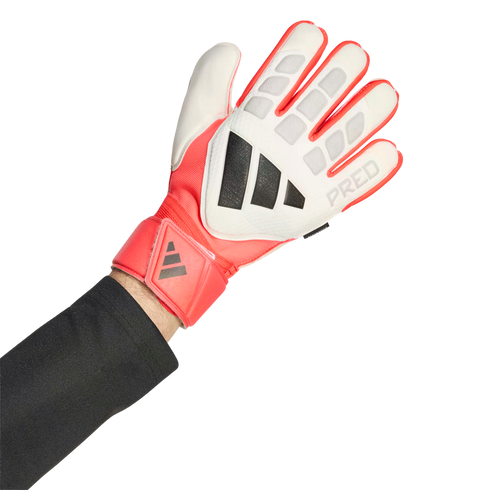 A person wearing a white, coral red, and black Adidas Predator goalkeeper glove against a black background.