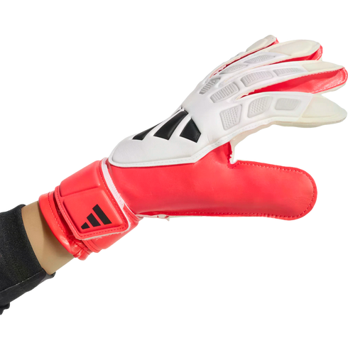 Red and white Adidas goalkeeper glove worn on a hand, set against a solid black background.