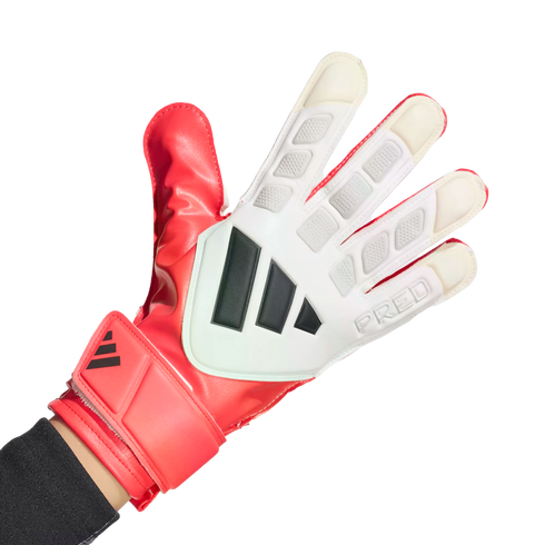 A hand wearing a red and white Adidas Predator goalkeeper glove with black stripes against a solid black background.