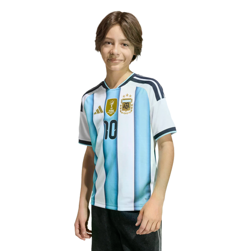 A young person with brown hair smiling in an Argentina national football team jersey with the number 10 and three stars, against a solid black background.