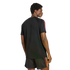 Rear view of a man looking over his shoulder, wearing a black t-shirt and matching shorts with pink, orange, and yellow stripes on the sides. He is set against a black background.