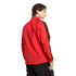 Rear-side view of a man in a red jacket with black patterned stripes on the sleeves and dark cargo pants against a black background.