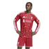 A man wearing a red and white patterned long-sleeved Liverpool F.C. jersey and matching shorts stands with his hands on his hips against a white background.