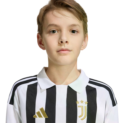 Portrait of a young boy with light brown hair wearing a black and white striped Juventus jersey against a white background.