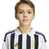 Portrait of a young boy with light brown hair wearing a black and white striped Juventus jersey against a white background.
