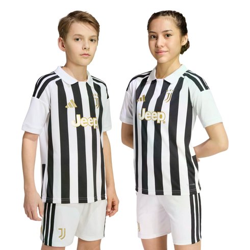 Two young people wearing matching black and white striped Juventus football kits with gold logos, standing against a plain white background.