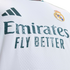 Close-up of a white Real Madrid soccer jersey featuring the Adidas logo, club crest, and "Emirates FLY BETTER" sponsor text with a graphic pattern inside the letters.