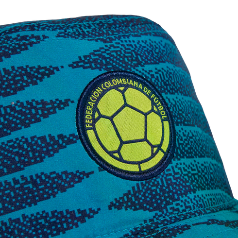 Teal hat with a blue pixelated pattern and an embroidered Colombian Football Federation patch featuring a lime green soccer ball.