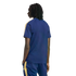 Back view of a person with dreadlocks in a navy blue t-shirt and matching pants with yellow and white stripes, standing against a black background.