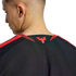 Close-up of a man's neck and the back of a black athletic jersey with a red phoenix logo on the collar and red shoulder stripes.
