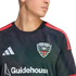 Close-up of a person wearing a black D.C. United soccer jersey with red shoulder stripes, featuring the team crest, white Adidas logo, and Guidehouse sponsor logo.