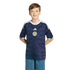 A young boy smiles while wearing a navy blue Scotland national football team jersey against a black background.