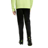 Back view of a person wearing a neon yellow long-sleeved jersey, black training pants, and black soccer cleats with neon accents against a black background.