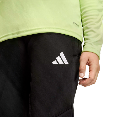 A person wearing a lime green long-sleeved shirt and black athletic pants with a white Adidas logo on the thigh.