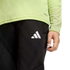 A person wearing a lime green long-sleeved shirt and black athletic pants with a white Adidas logo on the thigh.