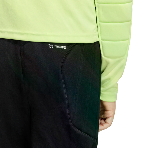 Close-up of a person wearing a lime green long-sleeved padded shirt and black pants with "CLIMACOOL" printed near the waistband against a black background.