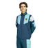 Man wearing a navy and light blue Adidas tracksuit with the Argentina Football Association logo on the chest, standing against a white background.