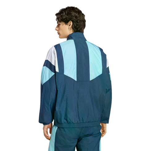 Rear view of a man wearing a blue and white geometric color-blocked windbreaker and matching track pants against a plain white background.