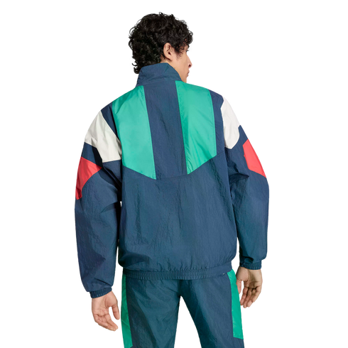 Rear view of a man wearing a retro-style, color-blocked tracksuit in navy blue, green, white, and red.