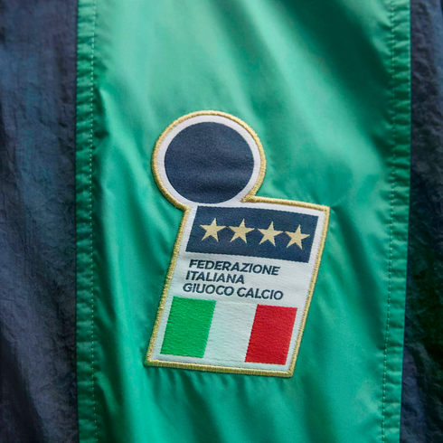 An embroidered FIGC logo patch on a green jacket, featuring four gold stars, the Italian flag, and the text "Federazione Italiana Giuoco Calcio".