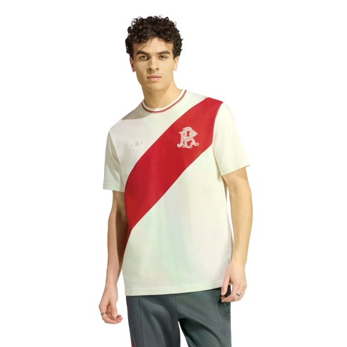 A young man with curly hair models a white Adidas t-shirt featuring a diagonal red sash and a stylized 'R' logo, paired with dark track pants.