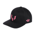 A black baseball cap with a pink Messi logo on the front and a pink Adidas Trefoil logo on the side, against a black background.