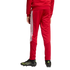 Rear view of a person wearing a red tracksuit with white stripes on the legs and black soccer cleats.
