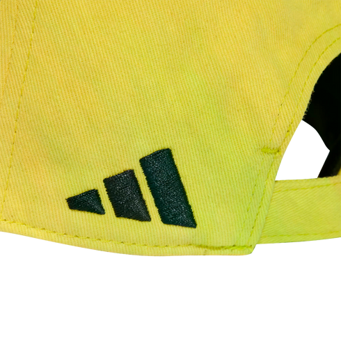 Close-up of the back of a bright yellow cap with the dark green Adidas mountain logo embroidered on the side.