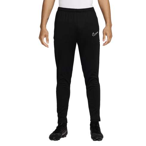 A person wears black Nike tapered training pants with a white logo and matching soccer cleats, standing against a plain white background.